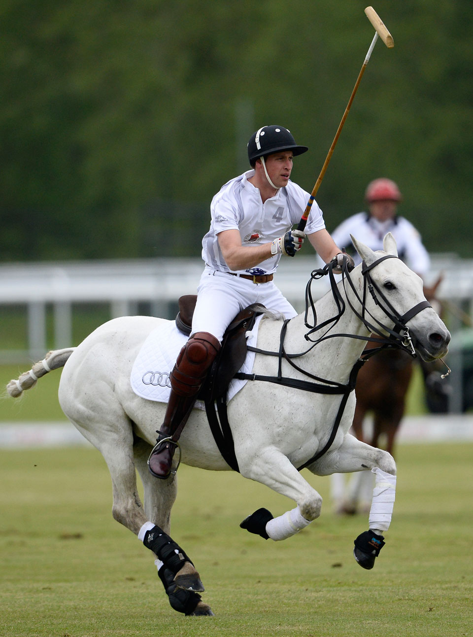 Prince William riding a horse in a polo match