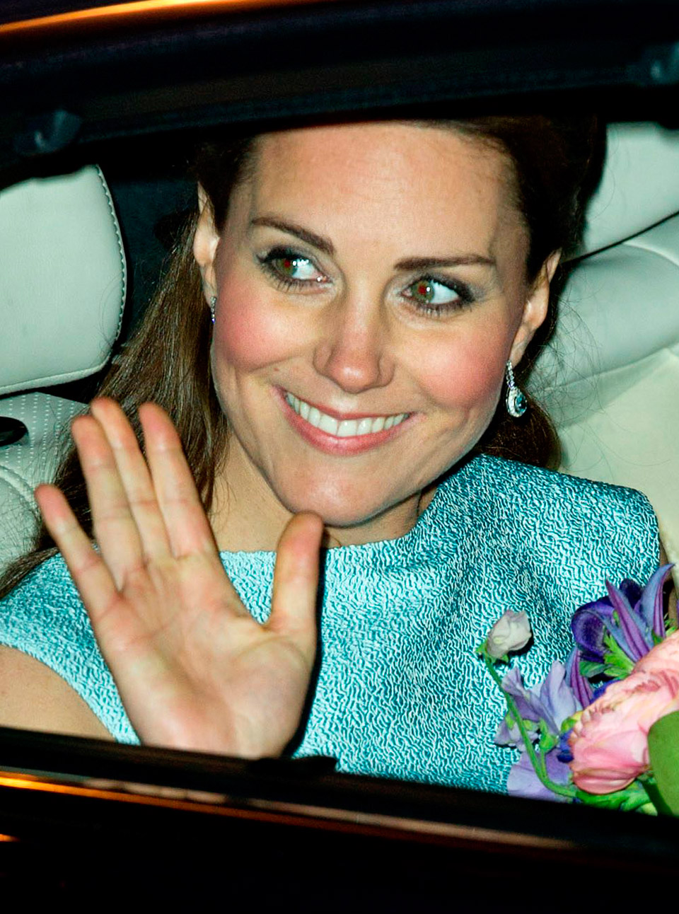 Kate Middleton wears a green dress and holds   flowers as she's driven away